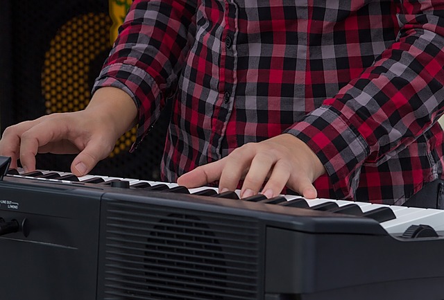 man in checkered shirt playing a digital piano