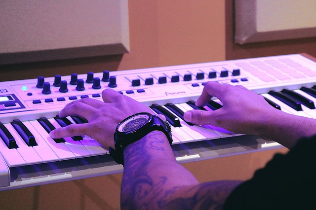 Man with a tattooed hand playing a digital piano